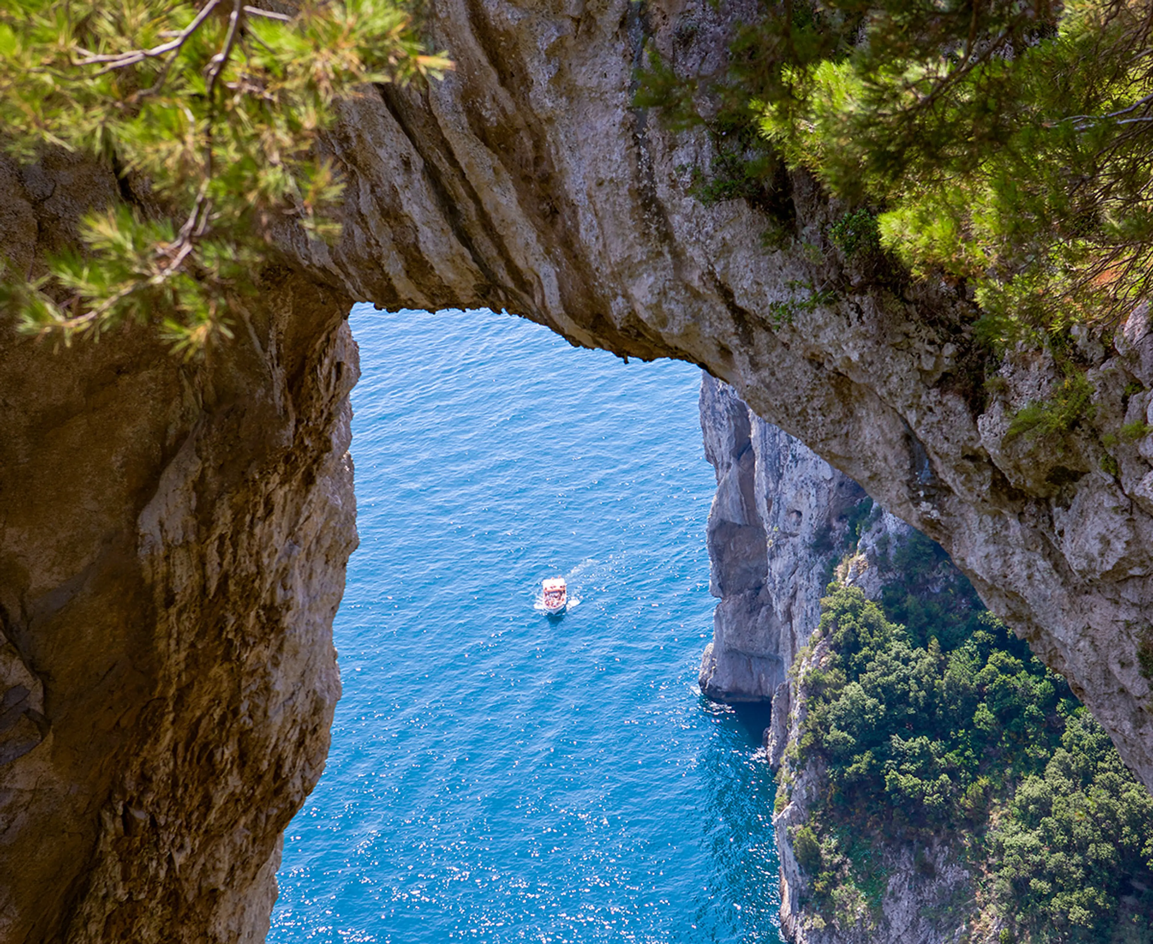 Arco di roccia sopra l'acqua turchese con un bagnante a Capri